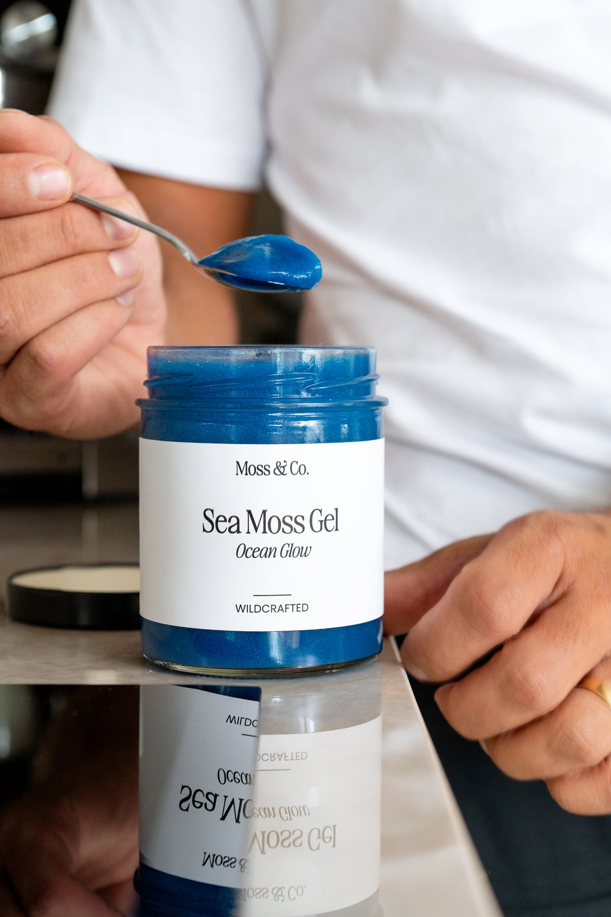 Sea moss gel Ocean Glow från Moss & Co. i en glasburk, visad med en sked och grönt blad i bakgrunden