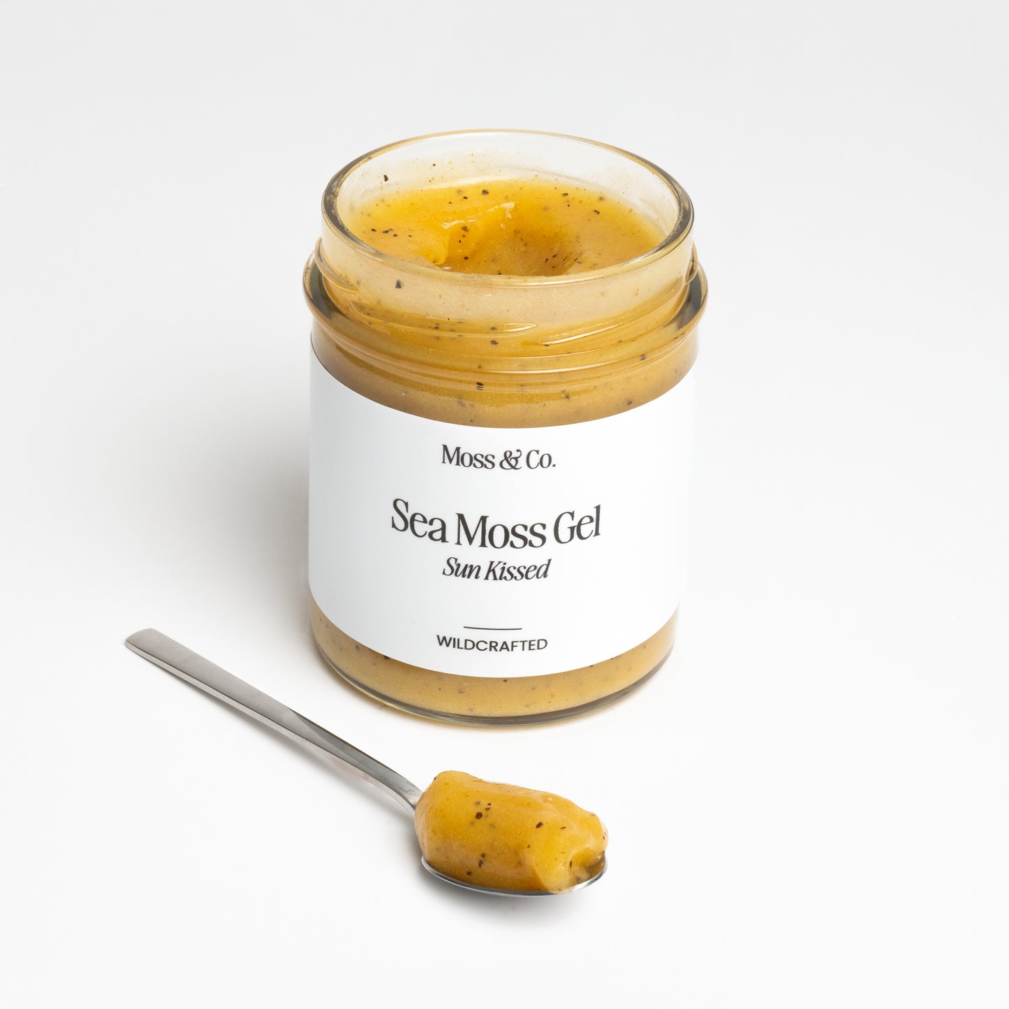 Röd flaska med Moss & Co. Sun Kissed Sea Moss Gel, närbild av produktetiketten på gelflaska.